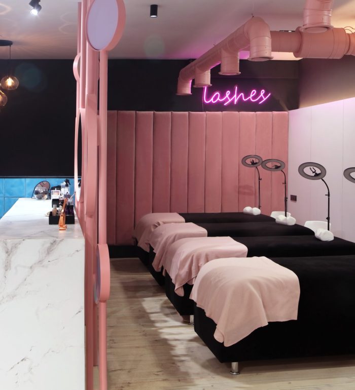 Interior of luxury stylish beauty salon.First plan pink armchairs and table for manicure and second plan place for eyelash extension .Pink concept design